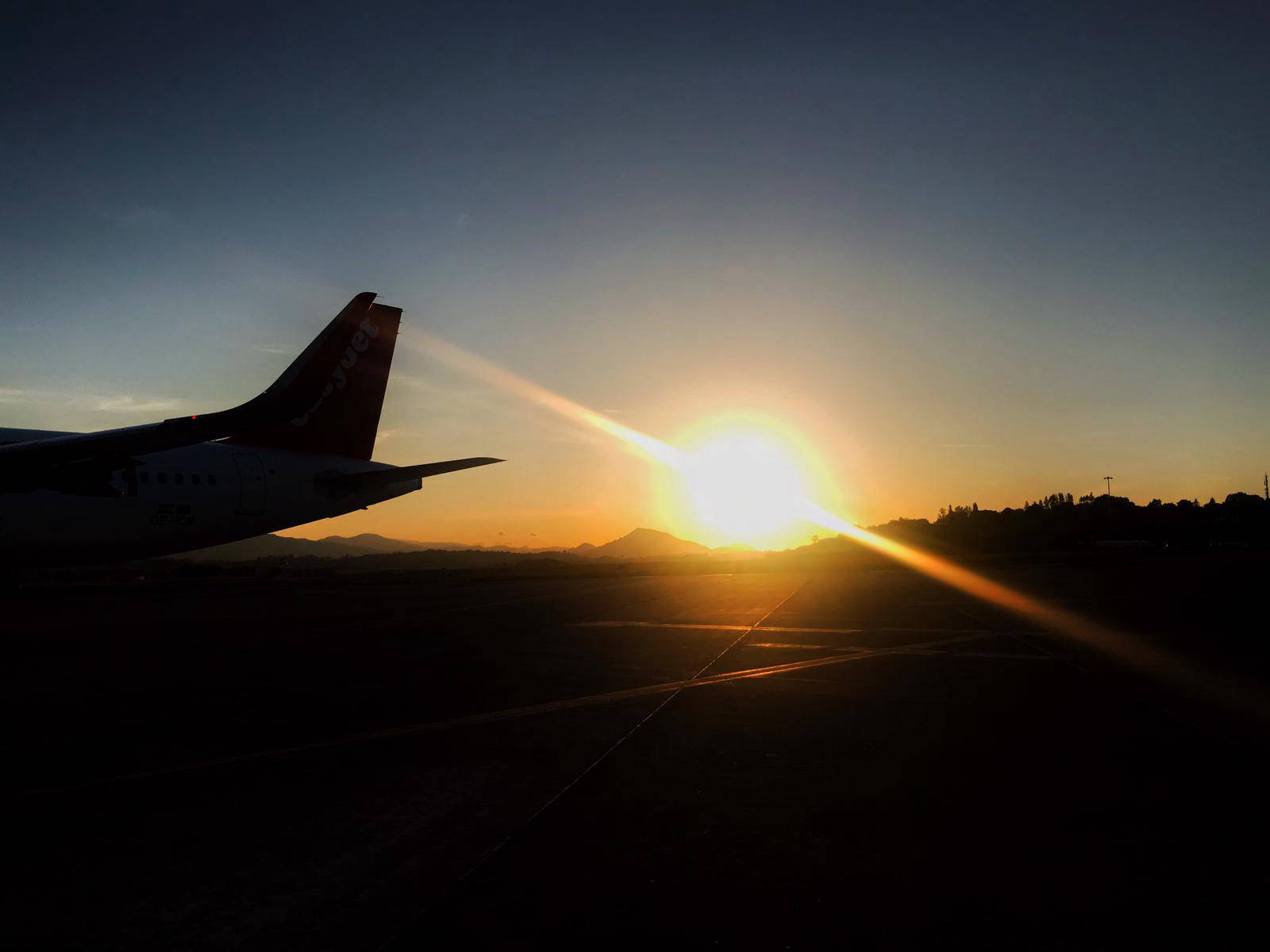 The tail of an airliner against the sunrise